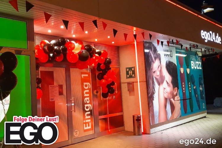 Eingang eines Clubs mit roten und schwarzen Luftballons und leuchtender Außenwerbung